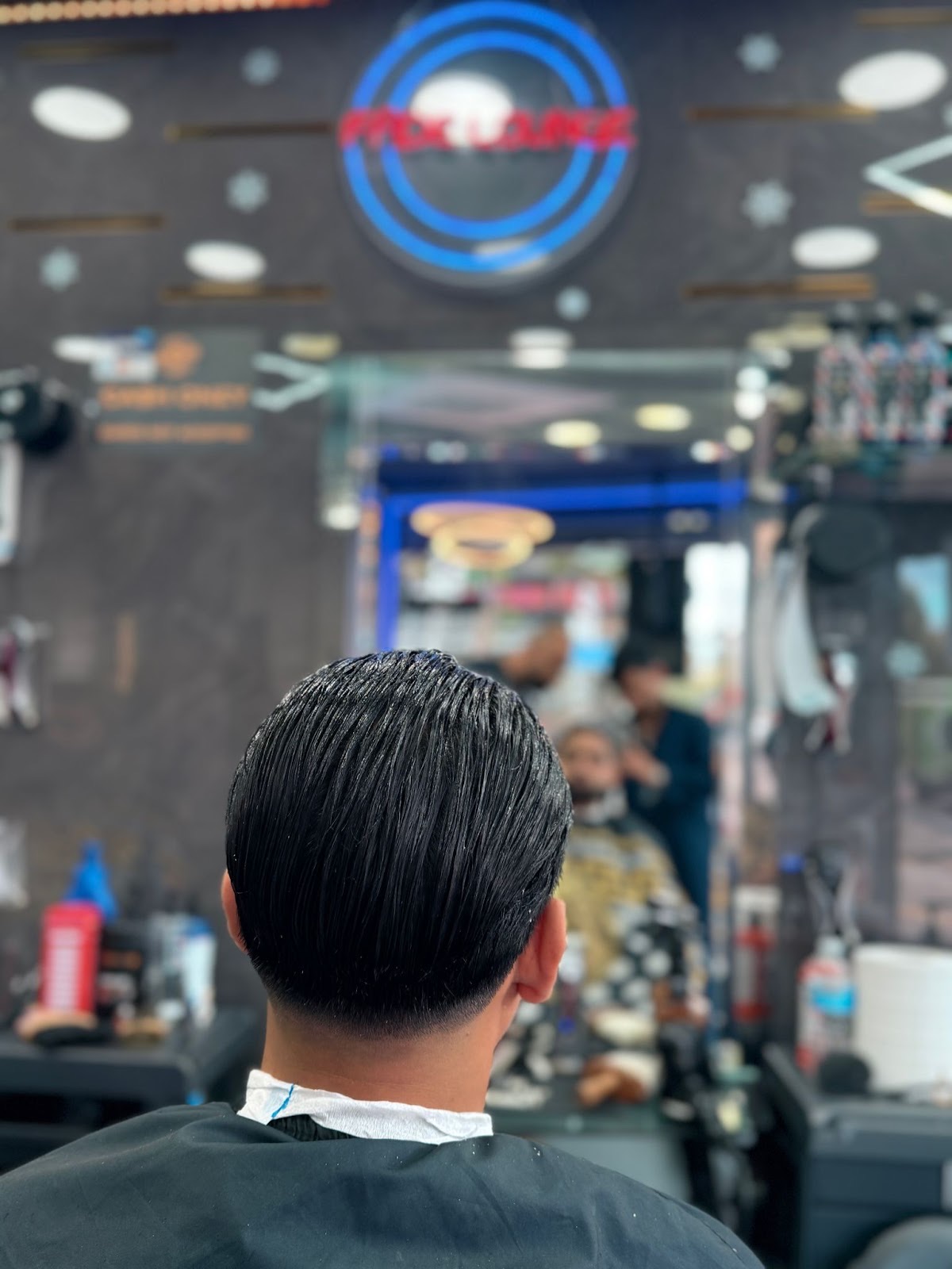 Back view of a finished dark slick-back cut with a clean neck taper